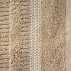 Close-up of the Home Co. Penny Self Stripe Face Cloth in taupe, showing the soft textured cotton loops, raised stripe pattern and decorative border detail.