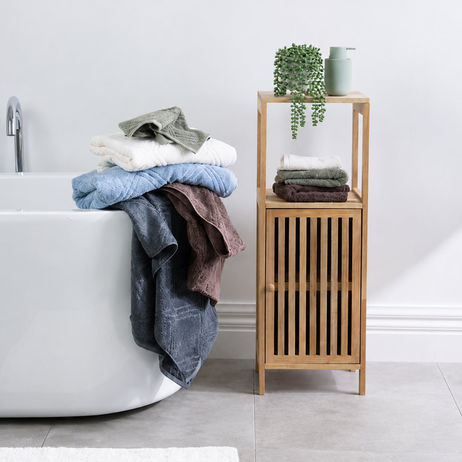 Design Republique Gemma Plush towel range displayed in a modern bathroom beside a bathtub and wooden storage cabinet.