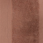 Close-up of a brick-coloured plush hand towel showing the textured cotton pile and ribbed border detailing.