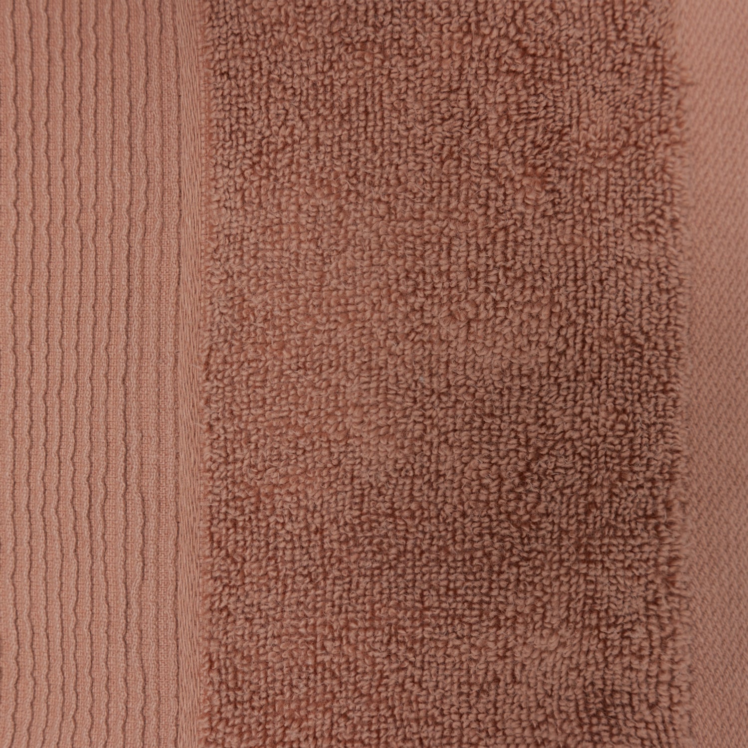 Close-up of a brick-coloured plush hand towel showing the textured cotton pile and ribbed border detailing.