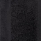 Close-up of a black plush face cloth showing the soft looped cotton texture and ribbed border detailing.