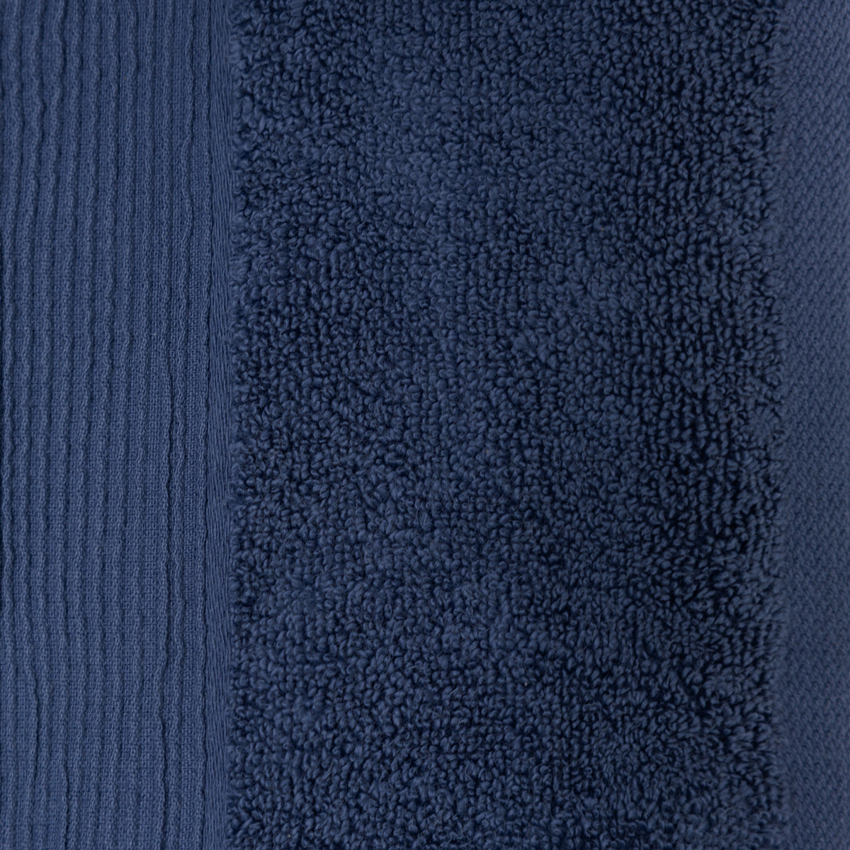 Close-up of a navy plush face cloth showing the dense cotton texture and ribbed border detailing.