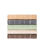Home Co. Sara Stitch Bath Sheets stacked in peach, charcoal, sage green, cream and mocha, featuring a soft textured finish and white stitched stripe detailing.