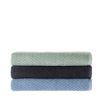 Three folded Quinny Popcorn bath sheets stacked in Sea Mist, Charcoal and Denim, featuring a raised textured pattern and plain woven borders.
