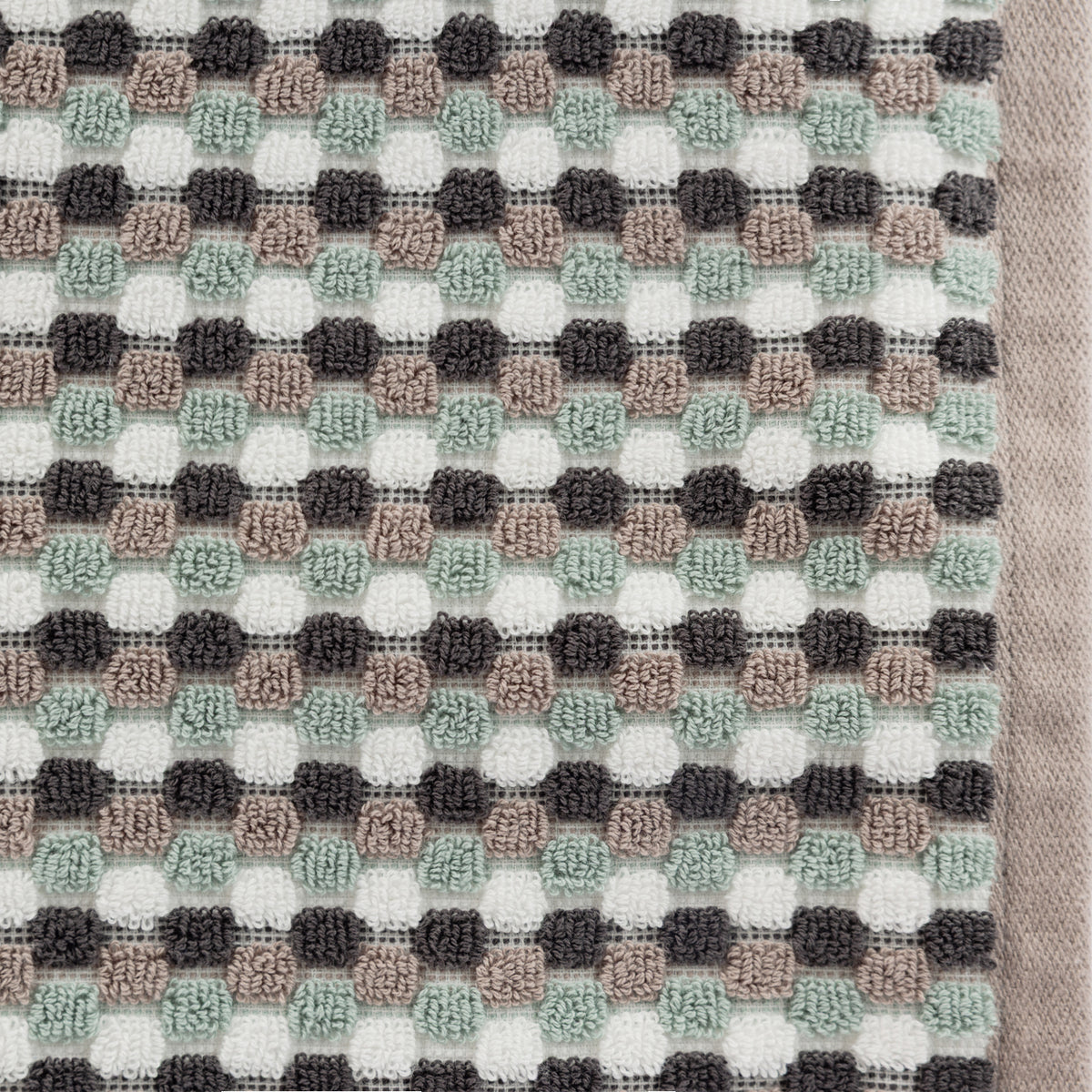 Close-up of the Taupe Quinny Popcorn towel, showing the raised popcorn-style check texture in sea mist, charcoal, taupe and white with a taupe woven border.