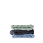 Three folded Quinny Popcorn hand towels stacked in Sea Mist, Charcoal and Denim, featuring the textured popcorn-style weave.