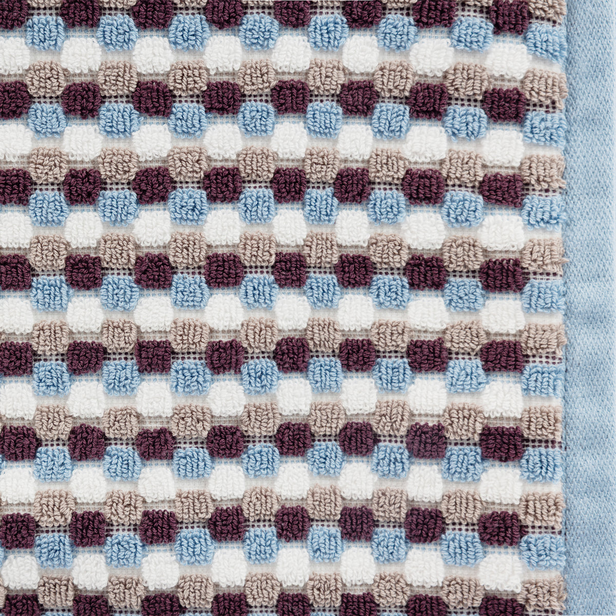Close-up of the Berry Quinny Popcorn towel, showing the raised popcorn-style check texture in blue, berry, taupe and white with a blue woven border.