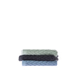 Three folded Quinny Popcorn face cloths stacked in Sea Mist, Charcoal and Denim, showing the raised woven texture and coordinating colours.