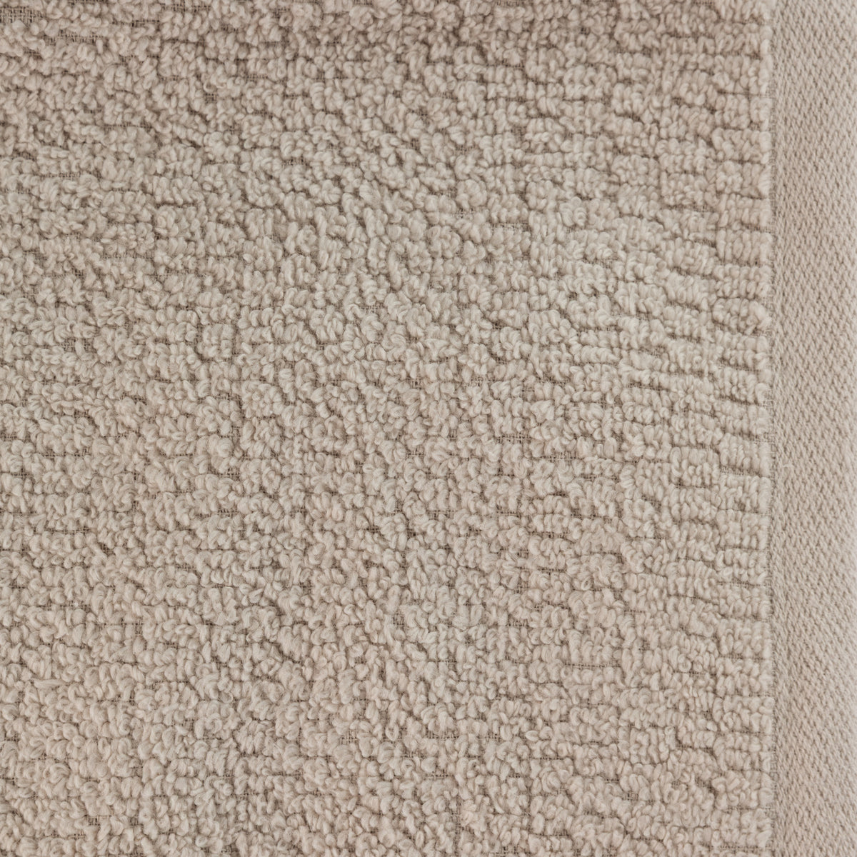 A close-up of the Home Co. Nevada Bath Towel 390gsm in Oatmeal, highlighting the neutral beige cotton fabric, textured looped surface and neatly woven border.