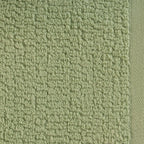 A close-up of the Home Co. Nevada Face Cloth 390gsm in Avocado, showcasing the soft sage green cotton fabric with a textured looped surface and neatly woven border.