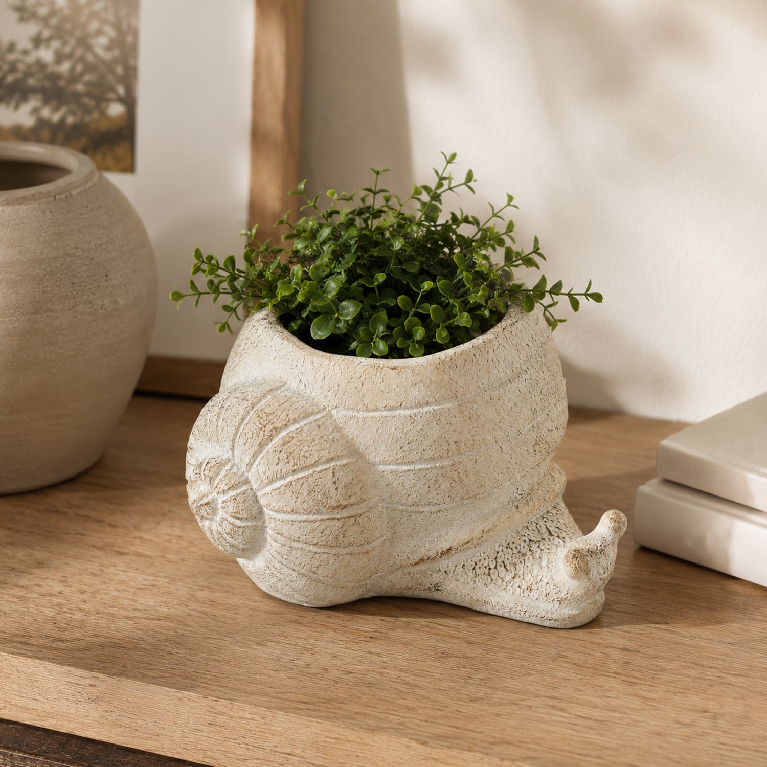 Design Republique Snail Planter Natural styled with a green plant on a wooden sideboard.