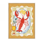 Design Republique Lobster Dish Framed Canvas featuring a red lobster on a plate with lemon slices, a drink glass and a warm yellow checked background.