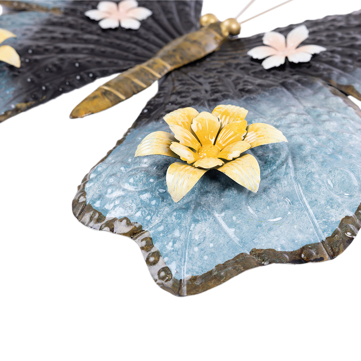 Close-up of the blue butterfly wall hanging showing the textured metal wing and raised yellow flower detail.