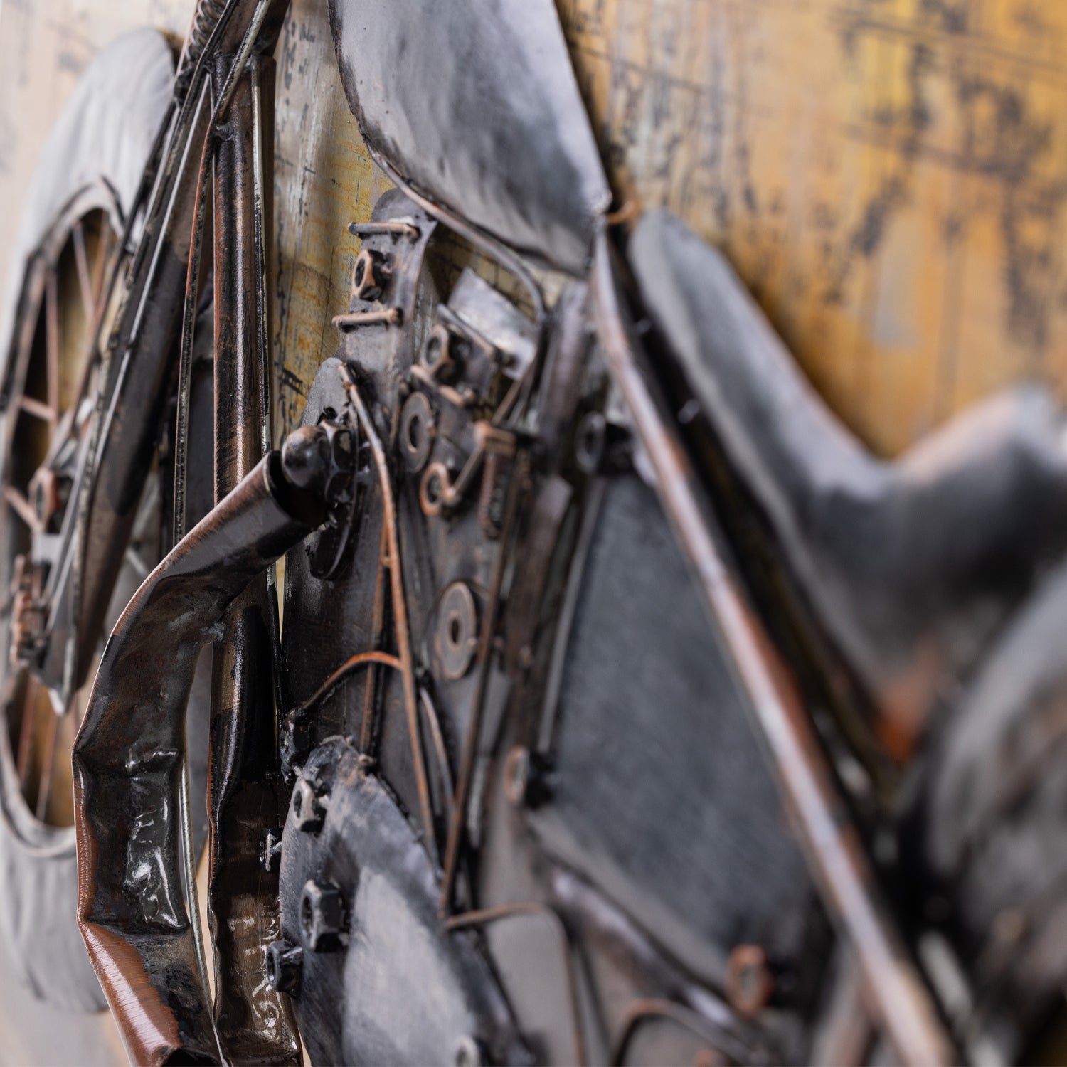 Close-up of the motorcycle metal wall art showing the raised handlebars, headlights, springs and layered metal detailing.