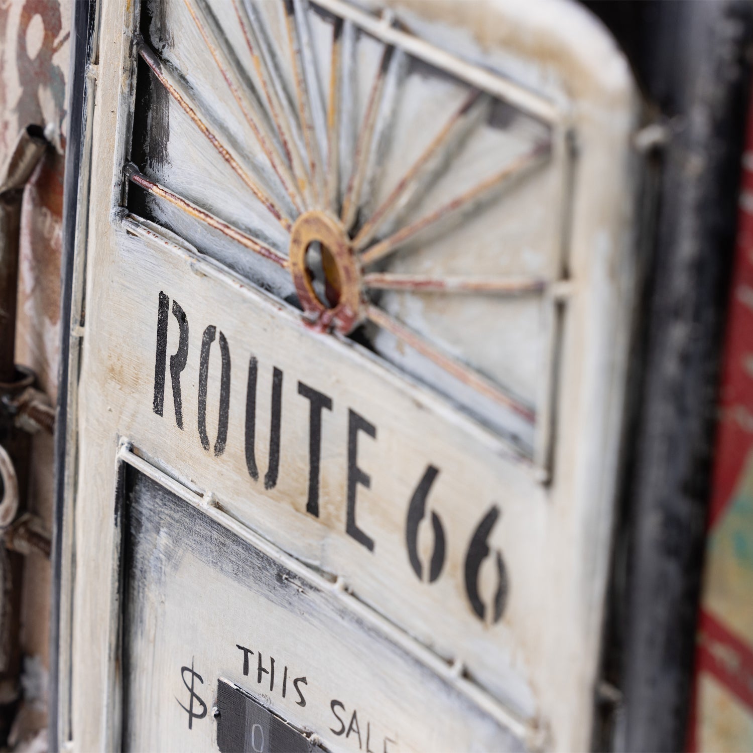 Close-up of a distressed decorative wall art featuring a vintage design and the text 'ROUTE 66' in black on an off-white painted panel.