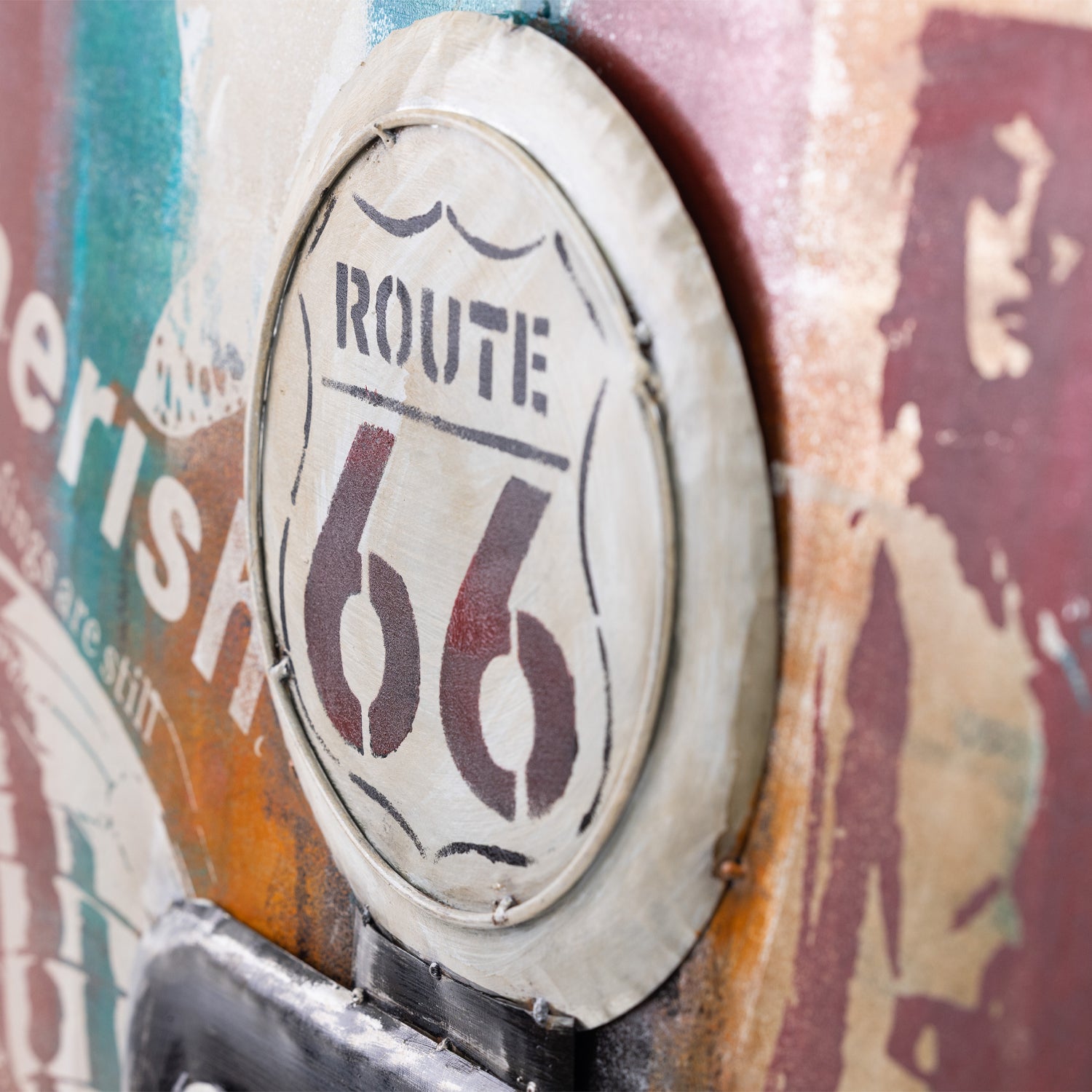 A close-up of a distressed Route 66 shield emblem on a weathered, multicolored surface with paint and vintage-style graphics.