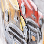 Close-up of a textured, multicolored wall art piece depicting stylized vintage cars in red, yellow, brown, and gray tones.