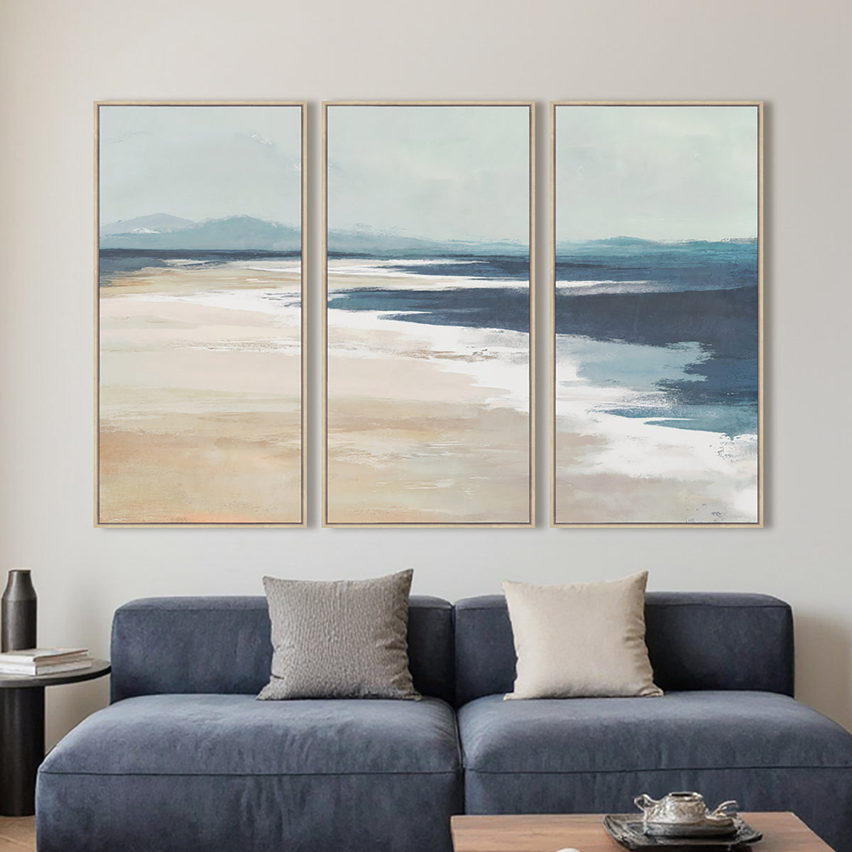 Lifestyle image showing the Cove On the Beach Framed 3 Piece displayed together above a blue sofa in a contemporary living room.