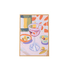 A framed still life painting featuring a pink wine glass, a bottle, and bowls of olives on a pale background, shown against a plain white backdrop.