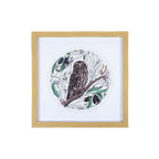 Square wall art with a natural wood-look frame, featuring a detailed brown Ruru perched on a branch amongst native Miro leaves and berries, surrounded by delicate black and white botanical illustrations in a circular design on a white background.