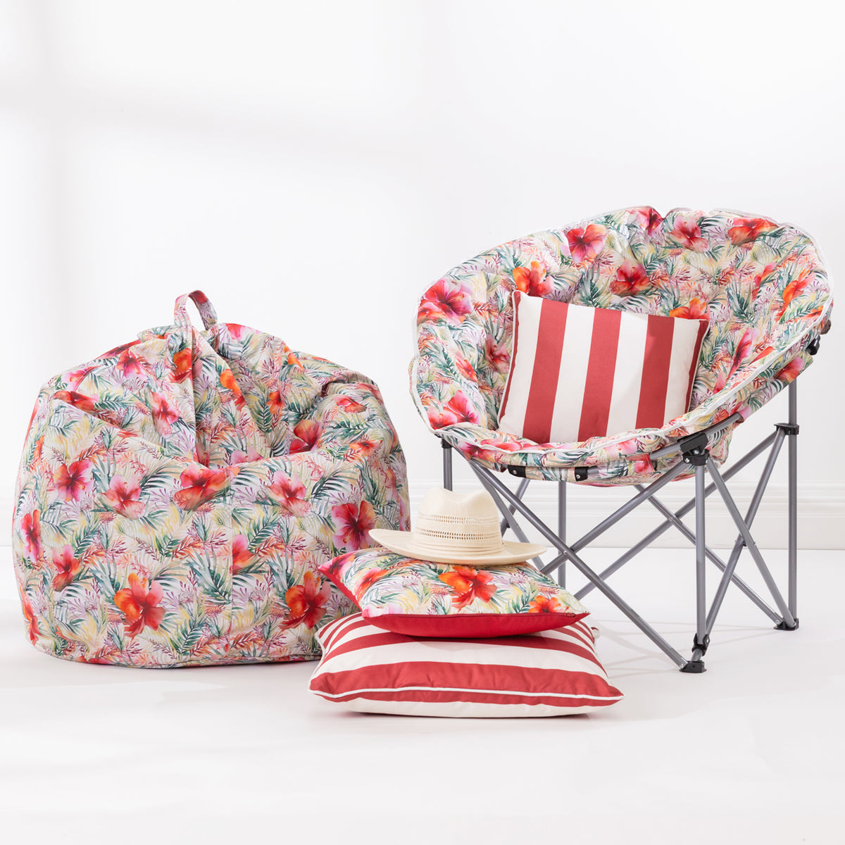 A tropical floral bean bag chair and matching moon chair set with red and white striped cushions, a red and white striped cushion, and a straw hat on a clean white background.