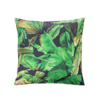 A outdoor cushion featuring a vibrant green tropical banana leaf pattern on a dark charcoal background, shown against a plain white studio backdrop.