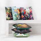 A collection of outdoor cushions with various colorful tropical and nature prints, arranged on and beside a white wooden bench against a white wall.