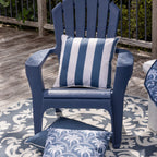 A blue outdoor Adirondack chair on a patterned rug with matching blue and white cushions, set on a wooden deck with a railing and greenery in the background.