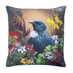 An outdoor euro cushion featuring a detailed illustration of a Tui bird surrounded by colorful native flowers on a warm background, with a dark green fabric border.