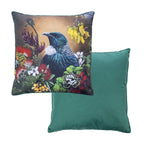 An outdoor euro cushion featuring a detailed print of a Tui bird surrounded by native flowers on a warm background, while the reverse of the cushion shows a solid green fabric.