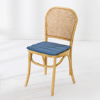 A dining chair with a natural woven cane backrest and a padded blue seat cushion, shown against a clean white studio background.