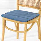 A dining chair with a natural woven cane backrest and a padded blue seat cushion, shown against a clean white studio background.