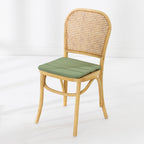 A dining chair with a natural woven cane backrest and a padded green seat cushion, shown against a clean white studio background.