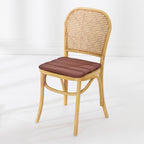 A dining chair with a natural woven cane backrest and a padded mocha seat cushion, shown against a clean white studio background.