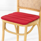 A dining chair with a natural woven cane backrest and a padded red seat cushion, shown against a clean white studio background.