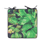 A square chair pad with a vibrant green tropical banana leaf print, featuring black tie straps at the top corners, shown against a plain white background.