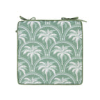 A chair pad cushion featuring a white palm tree and arch pattern, with two matching green ties at the top, shown on a plain white background.
