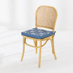 A light natural wood dining chair with a woven cane backrest and a blue seat cushion featuring a white palm pattern, shown against a clean white background.