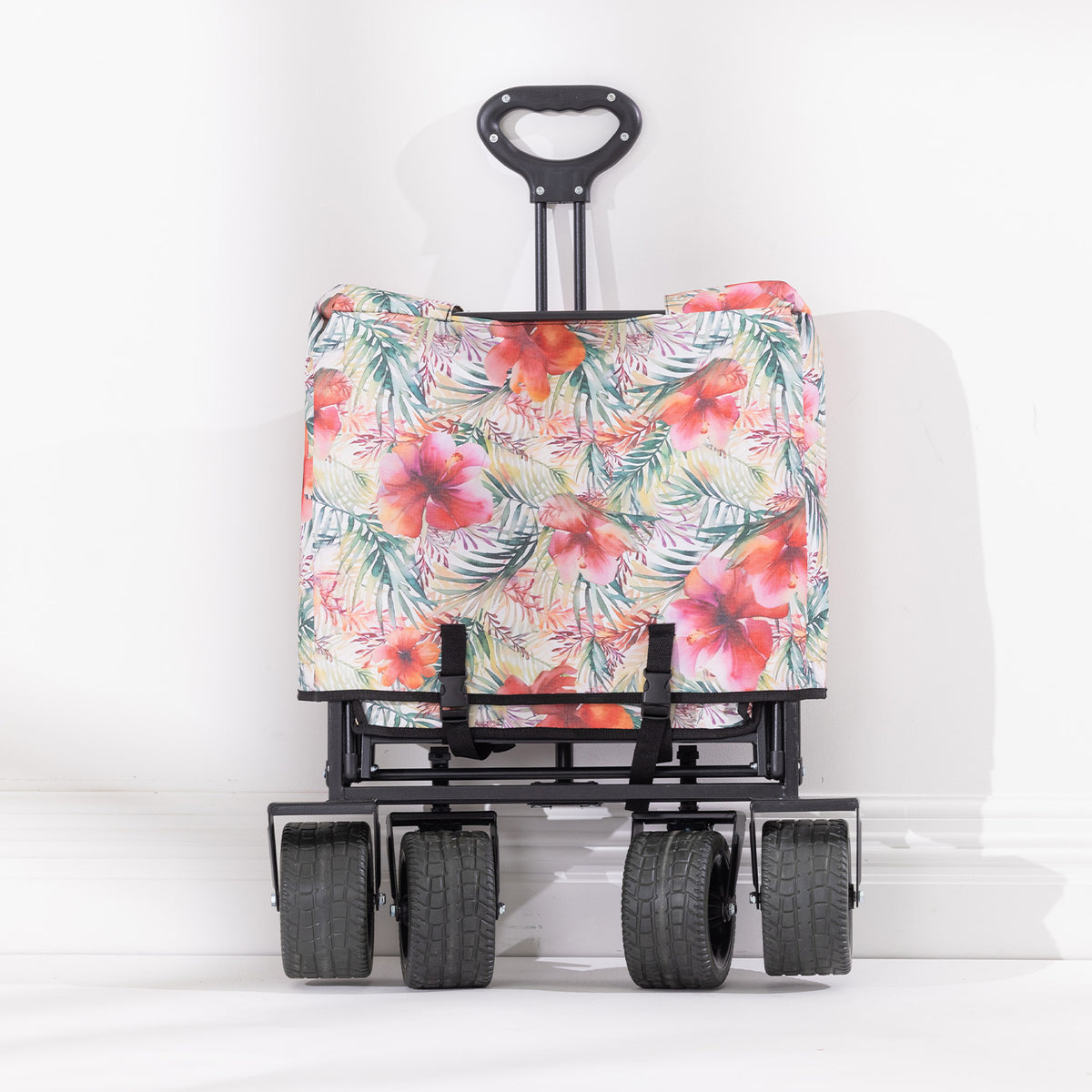 Folded hibiscus-print beach trolley shown upright with four wide wheels and an extended pull handle.