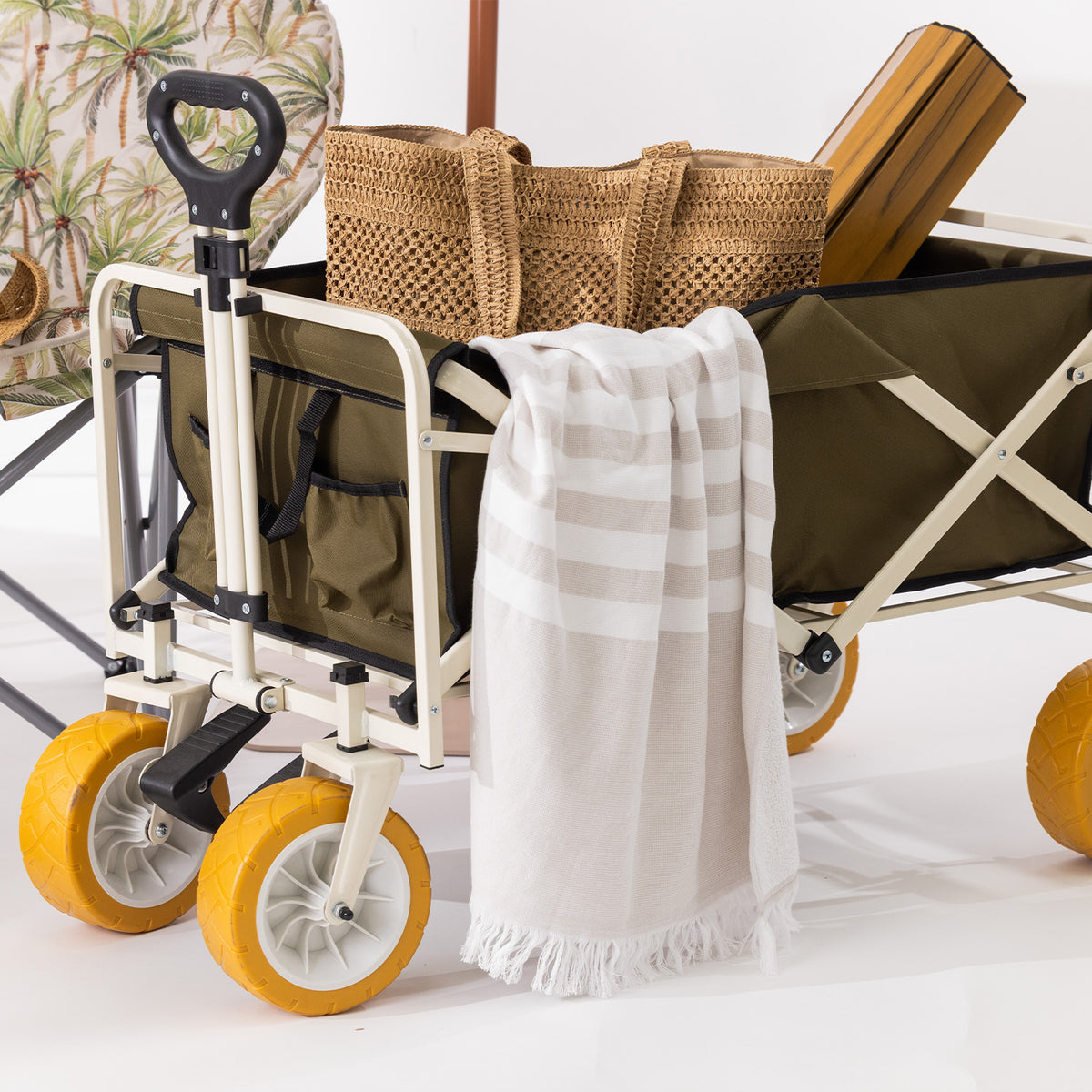 Green folding trolley loaded with outdoor essentials, featuring yellow all-terrain wheels, an extended pull handle and side storage pockets.