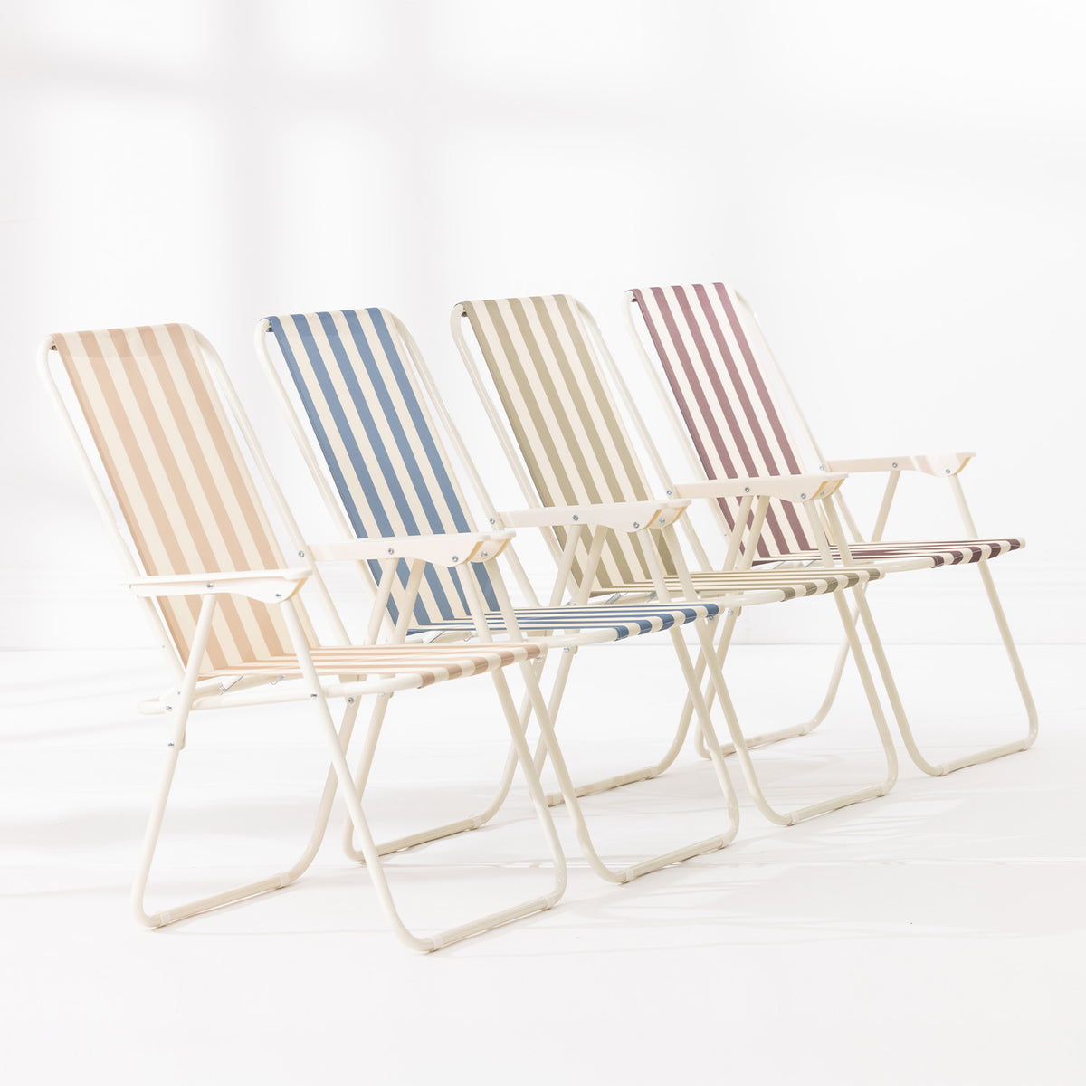 Four striped folding beach chairs in Green Stripe, Blue Stripe, Natural Stripe and Mocha arranged together on a white studio background.