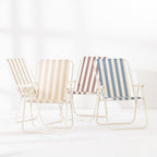 Four striped folding beach chairs in Green Stripe, Blue Stripe, Natural Stripe and Mocha arranged together at varying angles on a white studio background.