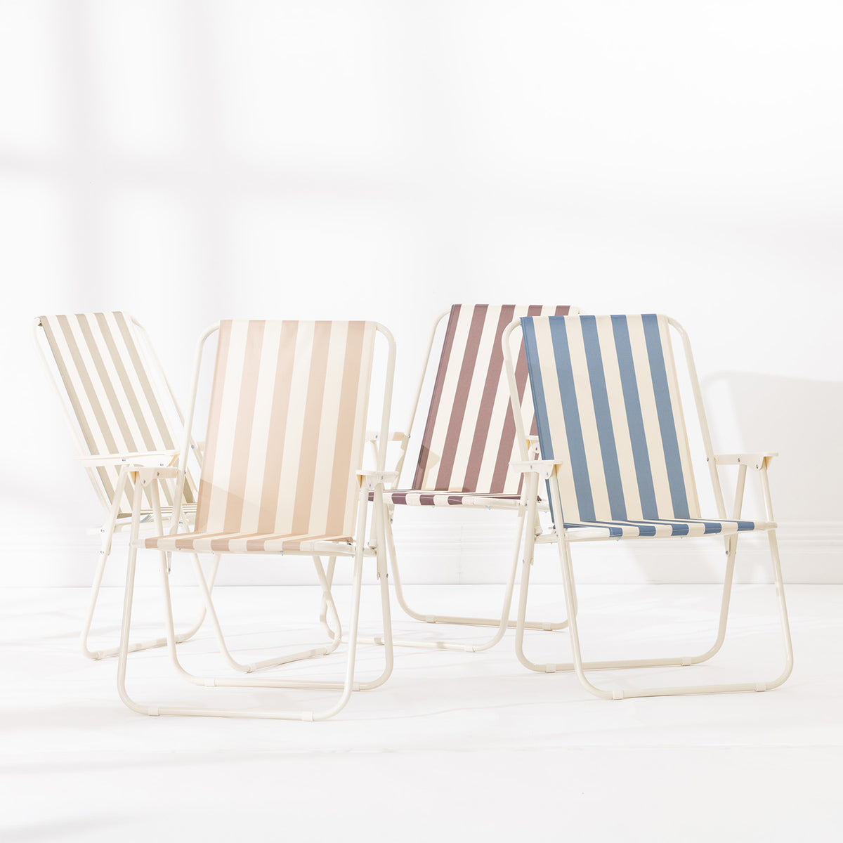 Four striped folding beach chairs in Green Stripe, Blue Stripe, Natural Stripe and Mocha arranged together at varying angles on a white studio background.