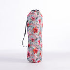 A drawstring moon chair bag with a vibrant tropical floral print in pink, red, green, and white, featuring a black carrying strap, set against a plain white background.