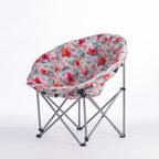 A folding moon chair with a curved, crescent-shaped seat upholstered in a vibrant tropical floral print, supported by a silver metal frame, shown on a white studio background.