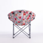 A folding moon chair with a curved, crescent-shaped seat upholstered in a vibrant tropical floral print, supported by a silver metal frame, shown on a white studio background.