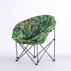 A round folding moon chair with a green tropical leaf print fabric cushion on a silver metal frame, photographed against a seamless white studio background.