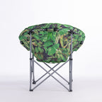 A round folding moon chair with a green tropical leaf print fabric cushion on a silver metal frame, photographed against a seamless white studio background.