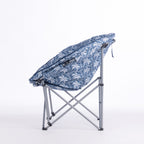 A folding moon chair with a blue and white palm tree patterned fabric seat cushion and a silver metal frame, shown on a plain white background.
