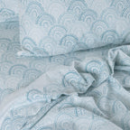 Teal and white patterned bedding set on a bed.